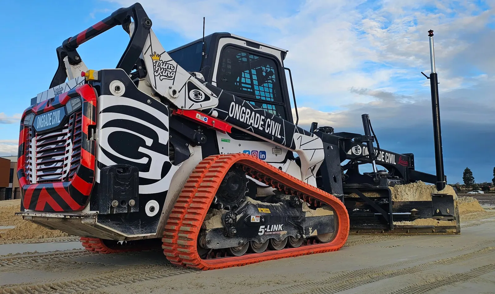 Ongrade Civil branded skid steer with laser-guided grading attachment on a prepared sand base